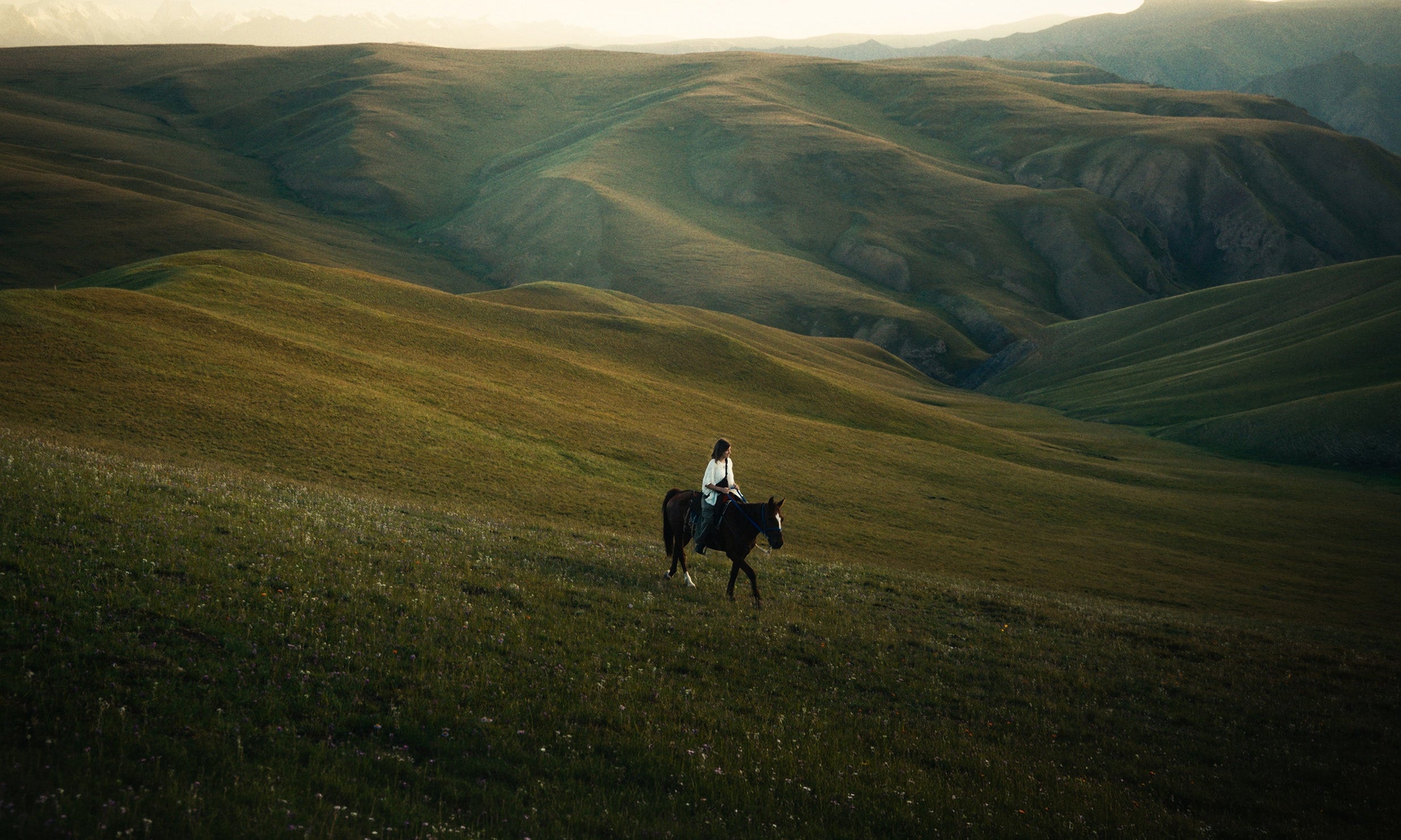 a person riding a horse in the hills of Kyrgyzstan at sunset on a trip with a local guide
