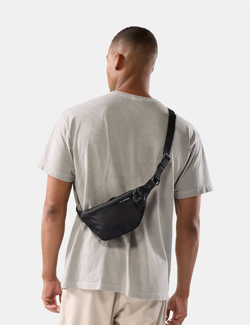 person wearing black sling bag on white background