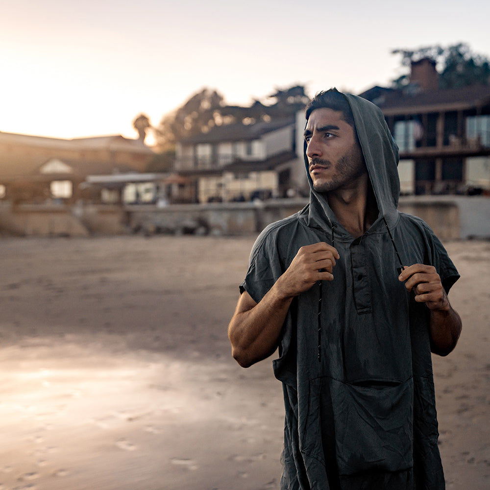 man on beach wearing gray poncho