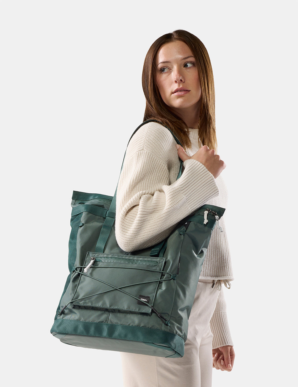 woman on white background wearing green tote over her shoulder