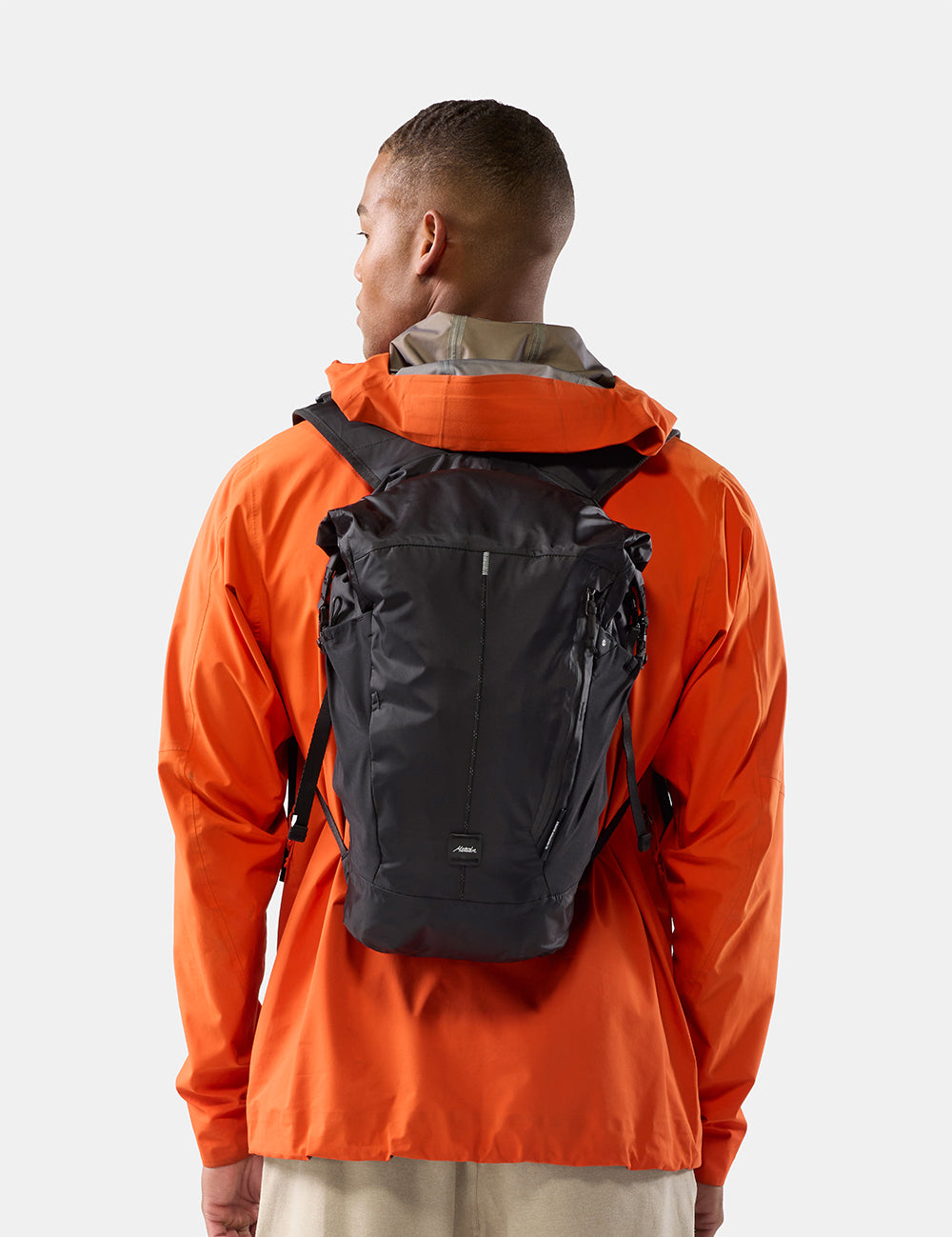 Person in bright orange wearing black backpack on white background