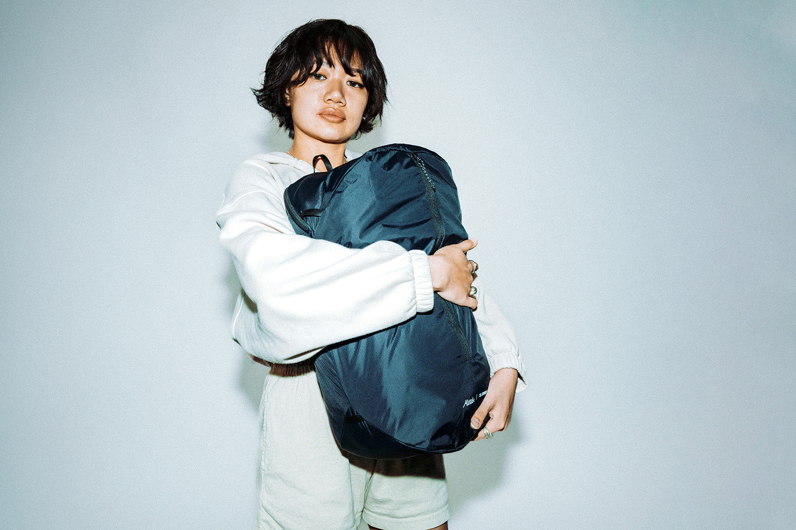 Person holding a black packable laundry bag against a plain background